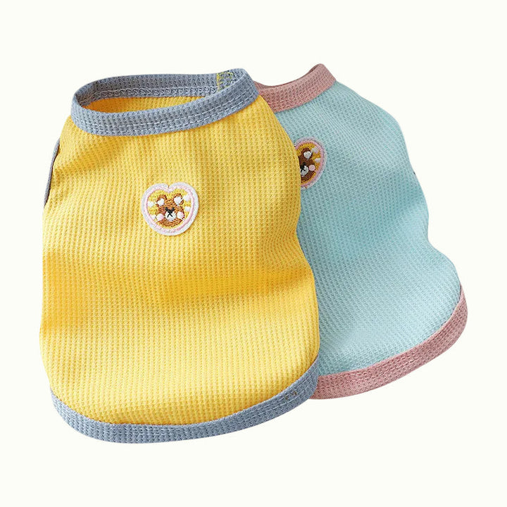 Two pastel bear small dog clothes, one yellow and one light blue, with heart designs on a white background.