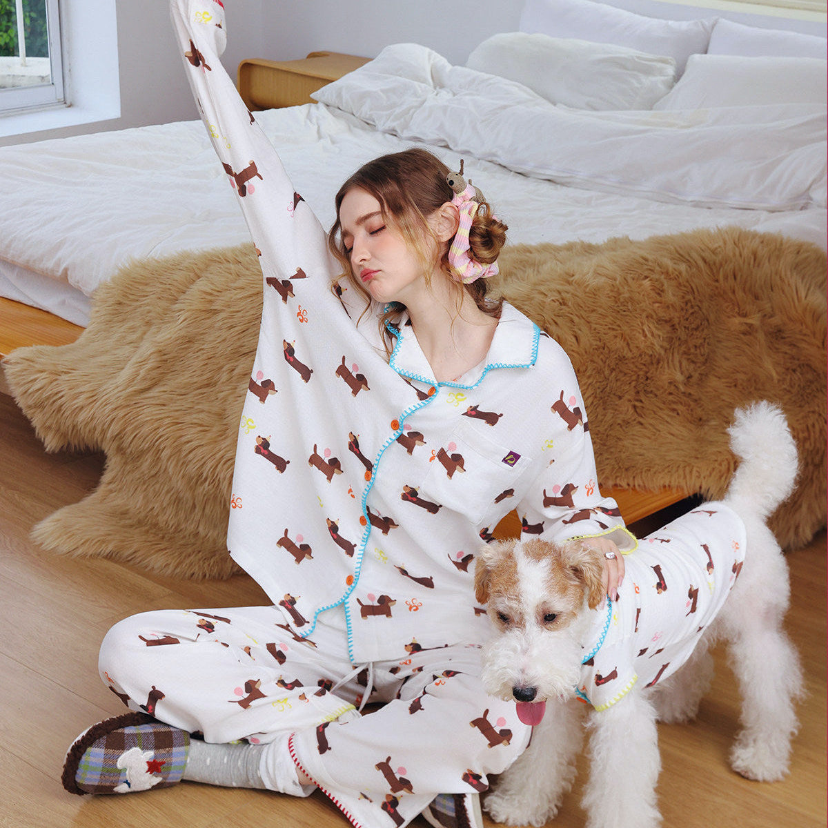 Woman and dog wearing matching pajamas in a cozy bedroom setting