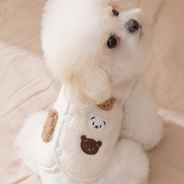 Small white dog wearing a white jacket with a bear design on a beige background 