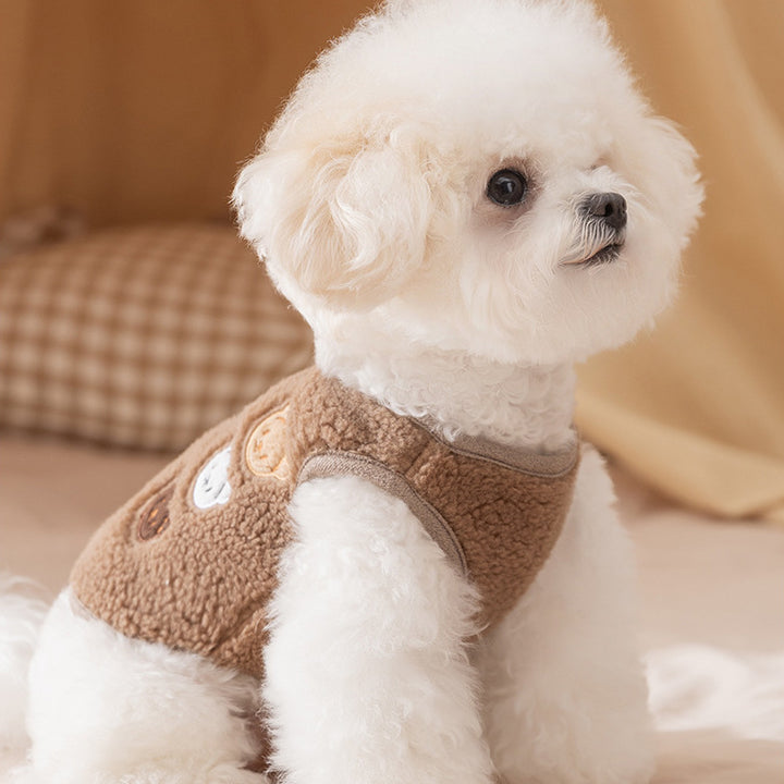 Small white dog wearing a brown fleece jacket on a blurred background