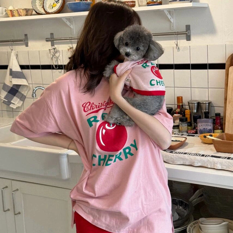 Person wearing a pink t-shirt with a dog in a kitchen