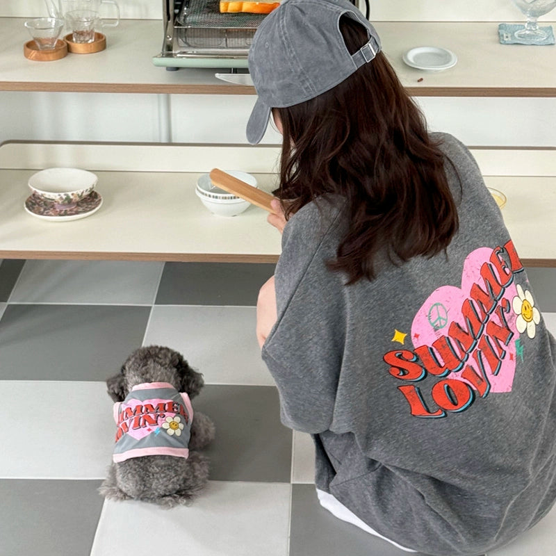 Person and dog wearing matching 'Summer Lovin'' outfits in a kitchen.
