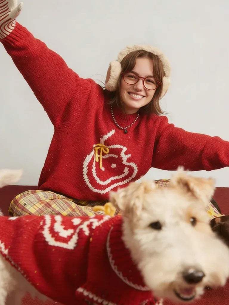 Woman wearing a red sweater with a dog also wearing a red sweater, both sitting on a couch.