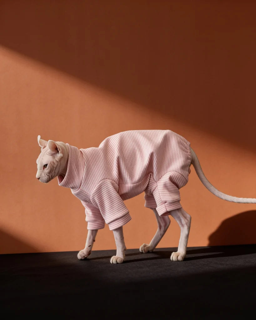Sphynx cat wearing a soft pink striped fleece onesie for fall and winter warmth