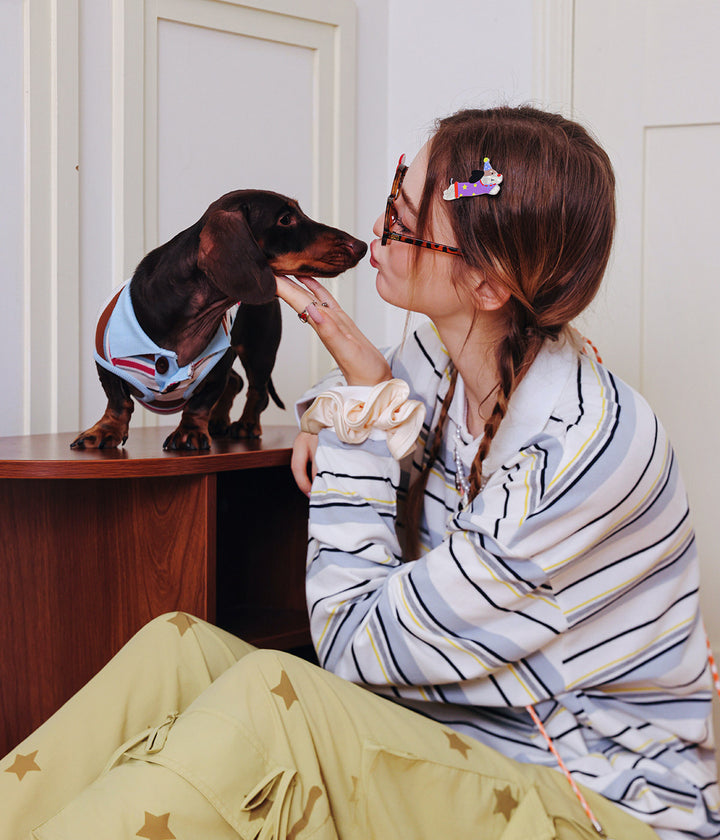 Woman and dog wearing matching outfits, both looking at each other.