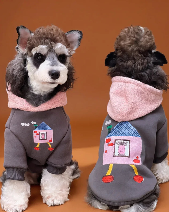 A small gray and white dog shown from the front and back wearing a gray hoodie with a pink hood and a cartoon house on the front and back